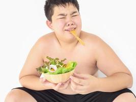 un ragazzo grasso odia mangiare l'insalata di verdure foto