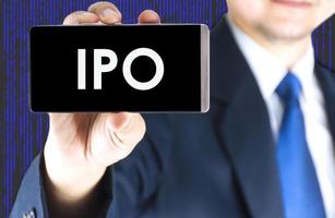 ipo, offerta pubblica iniziale, parola sullo schermo del telefono cellulare in mano sfocata giovane uomo d'affari e sfondo della tecnologia digitale, concetto di business foto