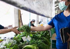 donna che acquista frutta fresca durante la diffusione del covid-19 nel mercato fresco locale della tailandia foto