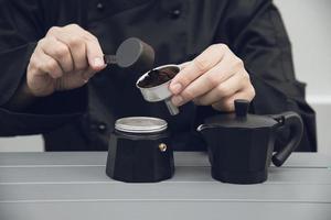 il barista asiatico sta usando il macinacaffè manuale per preparare il caffè caldo foto