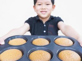 sfocatura del bambino che mostra, che serve i suoi muffin fatti in casa. la foto è messa a fuoco sui muffin.