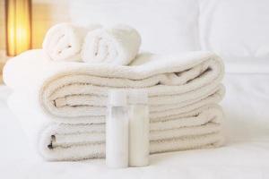 asciugamano dell'hotel con bottiglia di shampoo e sapone impostato sul letto bianco foto