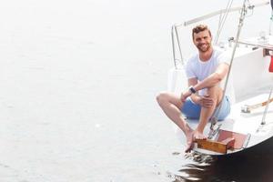 piacevole uomo seduto sul ponte dello yacht
