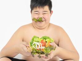 un ragazzo grasso mangia felicemente insalata di verdure foto