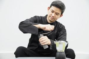 il barista asiatico sta usando il macinacaffè manuale per preparare il caffè caldo foto