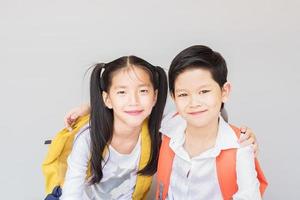 adorabili ragazzi della scuola delle coppie asiatiche, 7 e 10 anni, su sfondo grigio foto