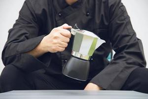 il barista asiatico sta usando il macinacaffè manuale per preparare il caffè caldo foto