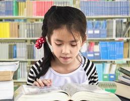 ragazza asiatica sta leggendo un libro in una biblioteca foto