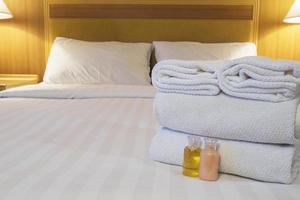 asciugamano dell'hotel con bottiglia di shampoo e sapone impostato sul letto bianco foto