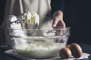 signora che fa la torta mettendo la crema con la spatola - concetto di cucina da forno fatto in casa foto