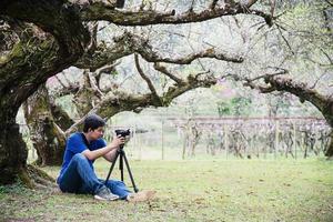 uomo di tourit che scatta foto in natura giardino di fiori di prugna