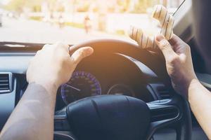 uomo che mangia ciambelle mentre guida l'auto - concetto di guida non sicuro multitasking foto