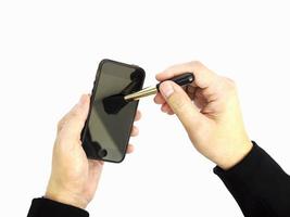 un uomo d'affari sta pulendo il suo telefono cellulare usando la spazzola per rimuovere la polvere. la foto è isolata su bianco.