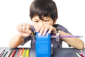 un ragazzo sta affilando la sua matita utilizzando un temperamatite meccanico su sfondo bianco foto