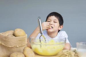 Ragazzo di 7 anni che prepara felicemente purè di patate foto