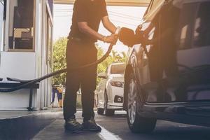 l'uomo sta mettendo ngv, veicolo a gas naturale, erogatore di testa in un'auto presso la stazione di servizio in Thailandia foto