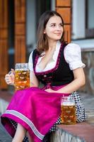 donna russa sexy in vestito bavarese che tiene boccali di birra. foto