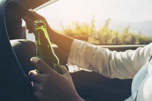 donna che tiene una bottiglia di birra mentre guida un'auto foto
