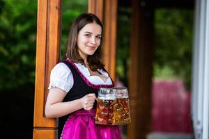 donna russa sexy in vestito bavarese che tiene boccali di birra. foto