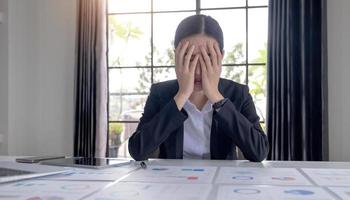 giovane donna d'affari asiatica che lavora su un tablet, è stressata ha mal di testa e pensa intensamente in ufficio. foto