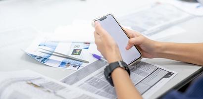 la mano femminile usa lo smartphone internet per controllare il tipo della pietra preziosa mentre studia nella classe delle pietre preziose. foto