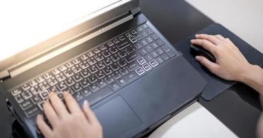 mano femminile che usa il laptop mentre è a casa a causa dell'epidemia di covid, conferenza online, attività di scrittura. foto