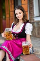 donna russa sexy in vestito bavarese che tiene boccali di birra. foto