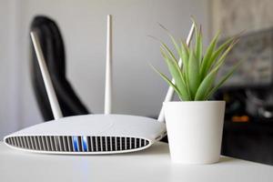 primo piano di un router wireless sul tavolo di casa con lo sfondo del computer desktop foto