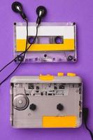 lettore di cassette con auricolari e cassetta su sfondo viola. foto