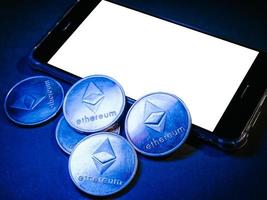 smartphone con schermo bianco e monete ethereum. concetto di valuta digitale. foto