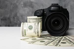 una fotocamera digitale nera e banconote su un tavolo bianco con sfondo grunge. foto