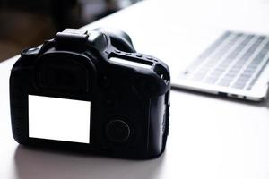 fotocamera digitale a schermo vuoto e un computer portatile su un tavolo. foto
