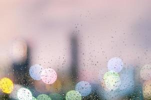 goccia di pioggia sulla finestra di vetro nella stagione dei monsoni con luce bokeh colorata dagli edifici della città foto