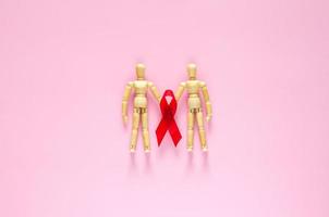 due modelli maschili in legno con nastro rosso per il minimo sesso sicuro, la salute sessuale mondiale e il concetto di giornata contro l'aids. foto