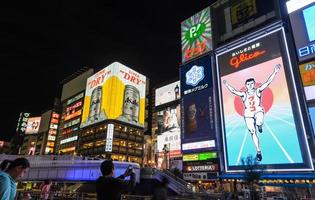 osaka, giappone 2016-il cartellone pubblicitario di glico man e altri insegne luminose a dontonbori, zona di namba, osaka, giappone. dotombori è una famosa zona della vita notturna e dell'intrattenimento a osaka. Giappone foto