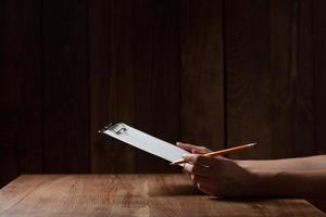 primo piano della mano della donna, scrivendo su carta sul tavolo di legno