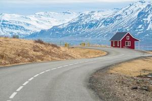 un piccolo cottage rosso situato nel fiordo orientale dell'Islanda con la strada di campagna una parte della circonvallazione principale passava questa regione orientale del paese. foto