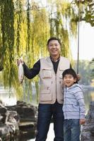 padre e figlio che mostrano la pesca pescata nel lago foto