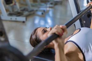 ragazza che si allena con la panca in una palestra foto