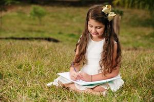 bambina con un libro in giardino. il bambino sta leggendo un libro in fattoria. studiare all'aperto in un giorno d'estate. campagna. ragazza brasiliana. foto