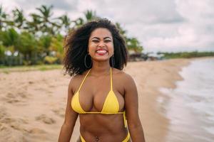 bella donna latinoamericana in bikini sulla spiaggia. giovane donna godendo le sue vacanze estive in una giornata di sole, sorridente e guardando la telecamera foto