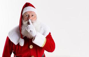 babbo natale che tiene l'indice vicino alla bocca. mantieni il segreto silenzioso confidenziale. foto