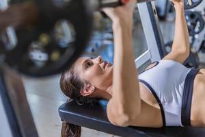 ragazza che si allena con la panca in una palestra foto