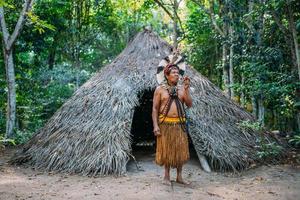 sciamano della tribù pataxo, che indossa un copricapo di piume e fuma la pipa. indiano brasiliano guardando a destra foto