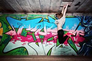 polonia, 2022 - ragazza alla moda in una posa di danza contro il muro dei graffiti foto