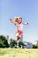 bambina che salta in alto nel parco cittadino in vestiti sporchi colorati. foto