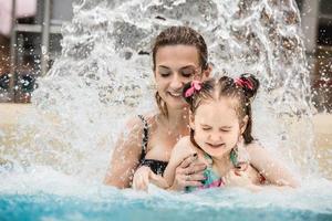 donna e sua figlia in piedi sotto una cascata foto