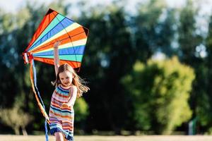 bambina sorridente che gioca con un aquilone colorato nel parco. foto