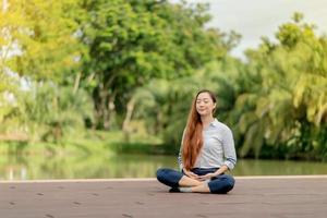 donna asiatica che indossa un abito bianco meditazione vicino al canale foto