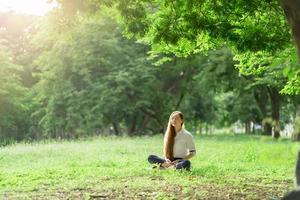 donna asiatica che indossa un abito bianco meditazione nel parco foto